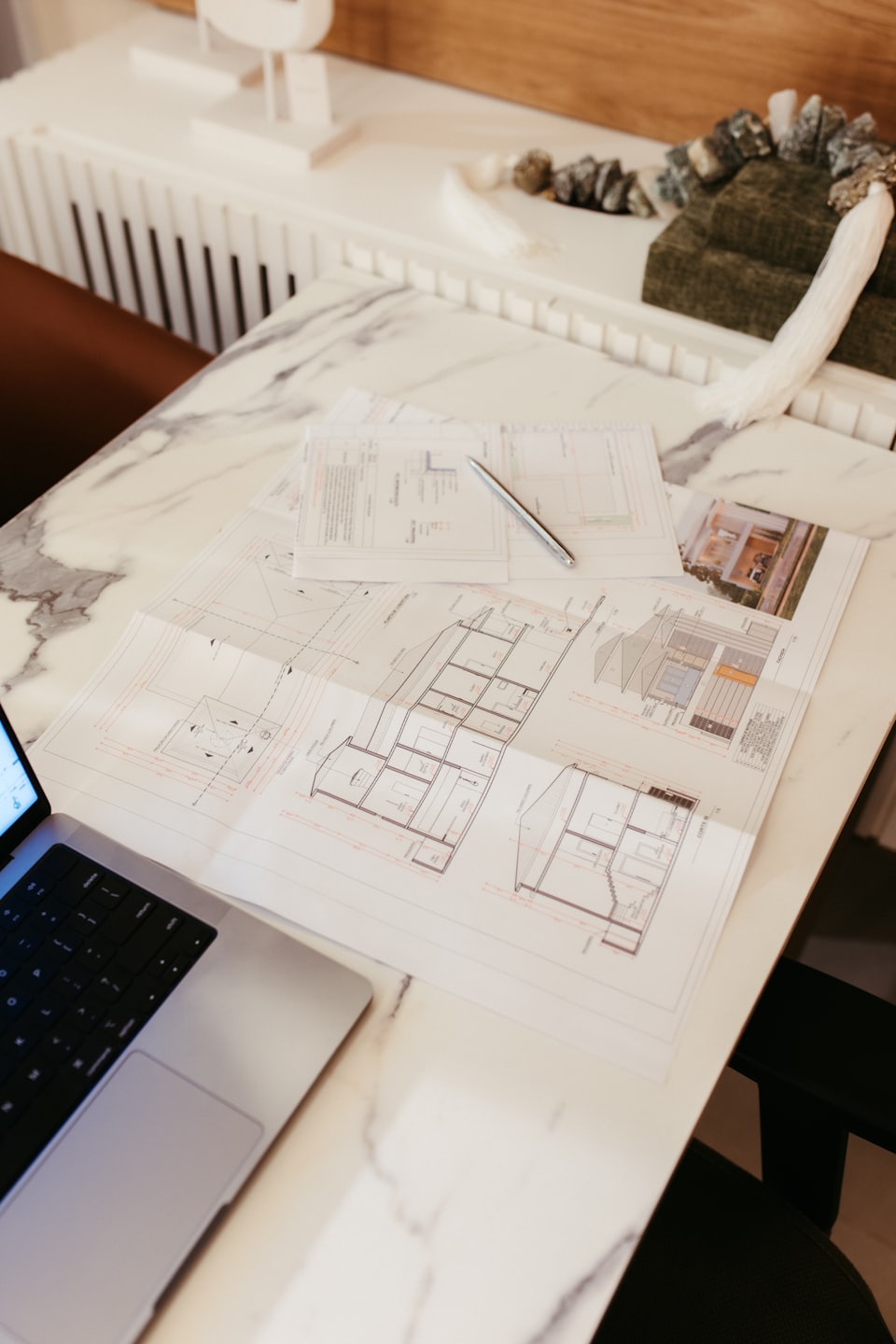 Architekturpläne und Laptop auf einem Marmortisch.