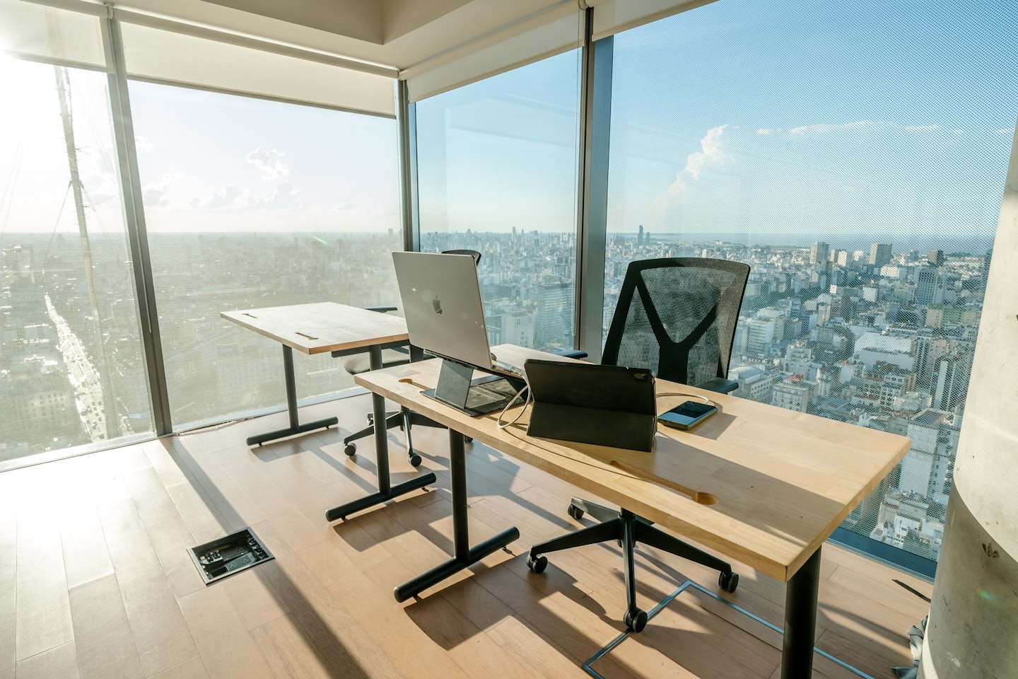 Moderne Bürotische mit Laptops mit Blick auf eine Stadtkulisse.